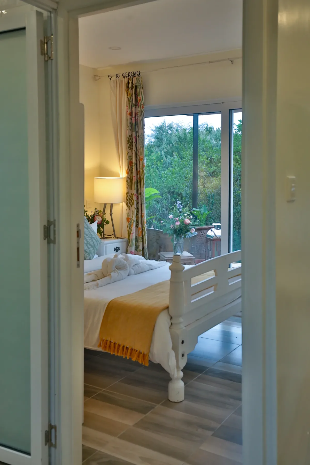 The bedroom seen through the doorway, forest framed in the window